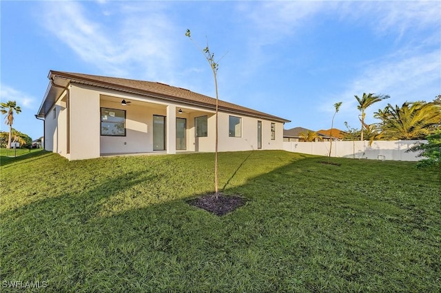 rear view of house featuring a lawn and ceiling fan