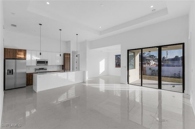 unfurnished living room featuring a tray ceiling and sink