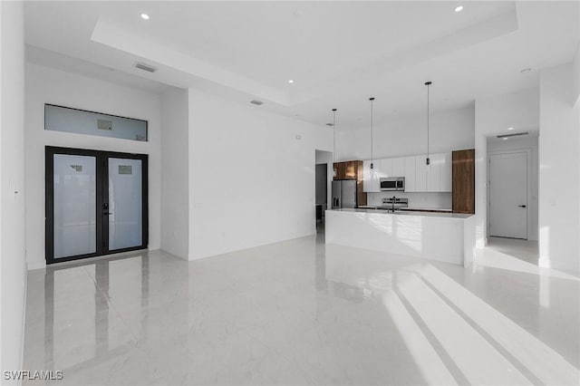 unfurnished living room featuring a tray ceiling and french doors