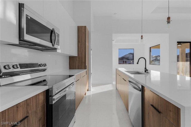 kitchen featuring white cabinets, appliances with stainless steel finishes, pendant lighting, and sink