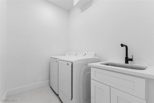 laundry area with cabinets, washing machine and dryer, and sink