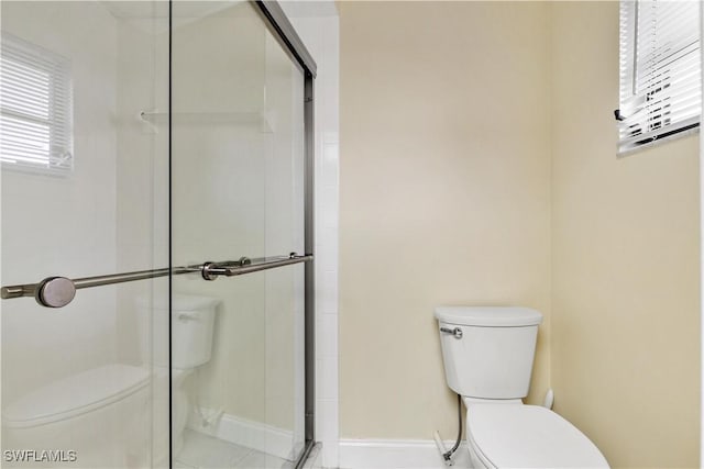 bathroom featuring a shower with shower door and toilet