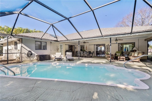 view of swimming pool featuring a patio, an outdoor hangout area, glass enclosure, and ceiling fan