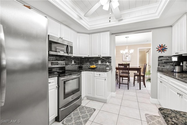 kitchen featuring a raised ceiling, stainless steel appliances, white cabinetry, and tasteful backsplash