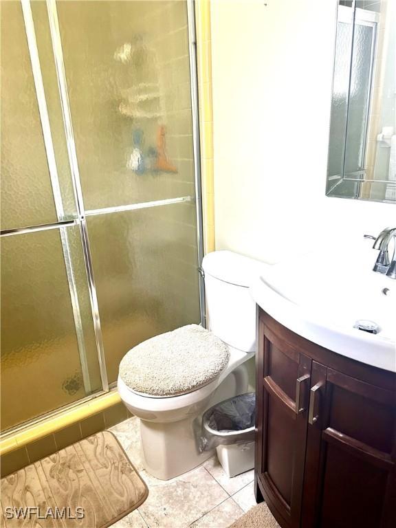 bathroom with tile patterned floors, vanity, toilet, and an enclosed shower