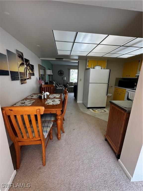 carpeted dining space with a drop ceiling