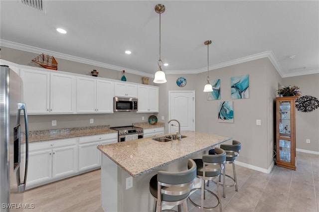 kitchen featuring sink, hanging light fixtures, stainless steel appliances, an island with sink, and white cabinets