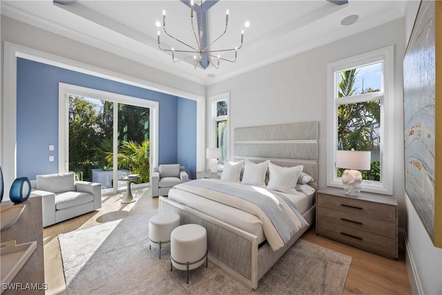 bedroom featuring multiple windows, crown molding, light hardwood / wood-style flooring, and a tray ceiling