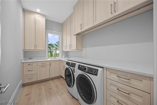 laundry area with cabinets, separate washer and dryer, and light hardwood / wood-style flooring