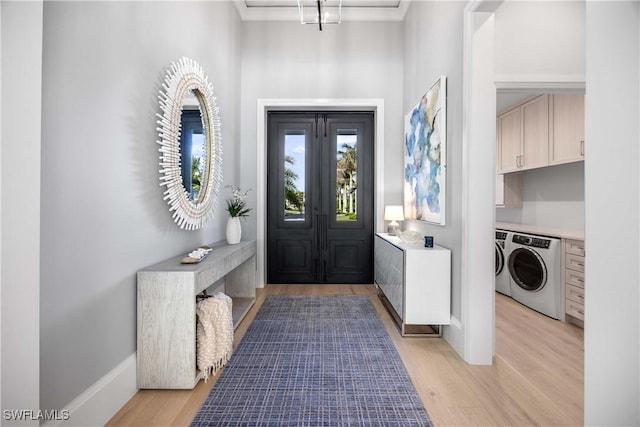 foyer with independent washer and dryer, crown molding, and light hardwood / wood-style flooring