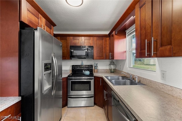 kitchen featuring sink, light tile patterned flooring, stainless steel appliances, and a textured ceiling