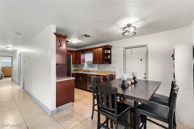 tiled dining space featuring a textured ceiling, a wealth of natural light, and sink