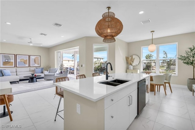 kitchen with a sink, white cabinetry, open floor plan, hanging light fixtures, and dishwasher