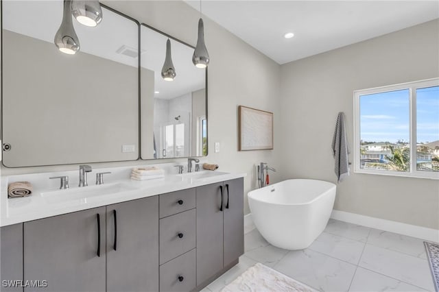 bathroom featuring marble finish floor, a freestanding bath, visible vents, and a sink