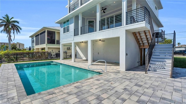 rear view of property featuring ceiling fan, a fenced in pool, a balcony, and a patio