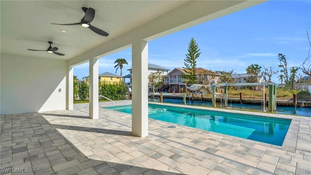 view of swimming pool featuring ceiling fan, a water view, and a patio