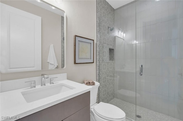 bathroom featuring a shower stall, toilet, and vanity