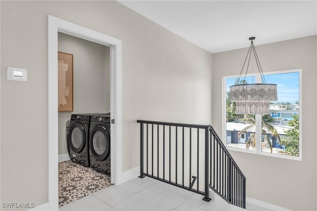 washroom with washer and dryer, a healthy amount of sunlight, and a chandelier