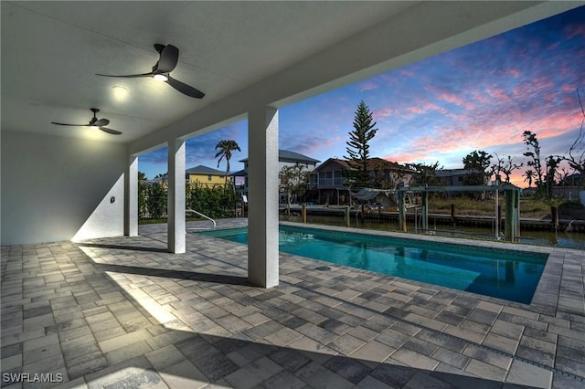 pool at dusk featuring a patio area and ceiling fan