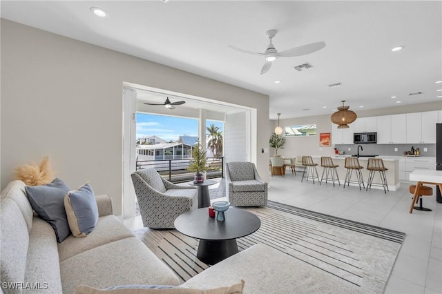 tiled living room featuring ceiling fan and sink