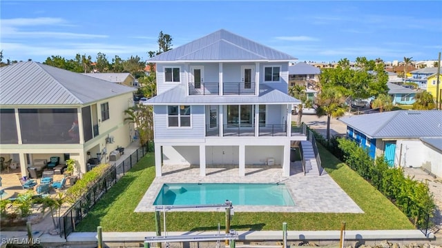 rear view of house with a balcony, a fenced in pool, a patio, and a yard