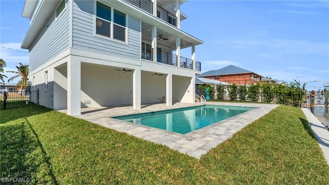 back of house with a balcony, fence, a ceiling fan, a fenced in pool, and a patio area