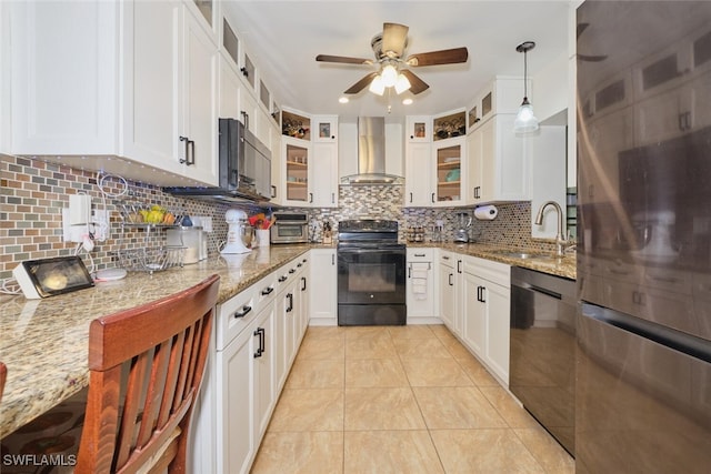 kitchen with light stone countertops, appliances with stainless steel finishes, wall chimney exhaust hood, sink, and white cabinetry