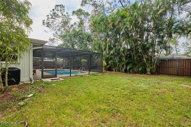 view of yard with a fenced in pool and glass enclosure