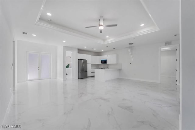 unfurnished living room featuring ceiling fan and a tray ceiling