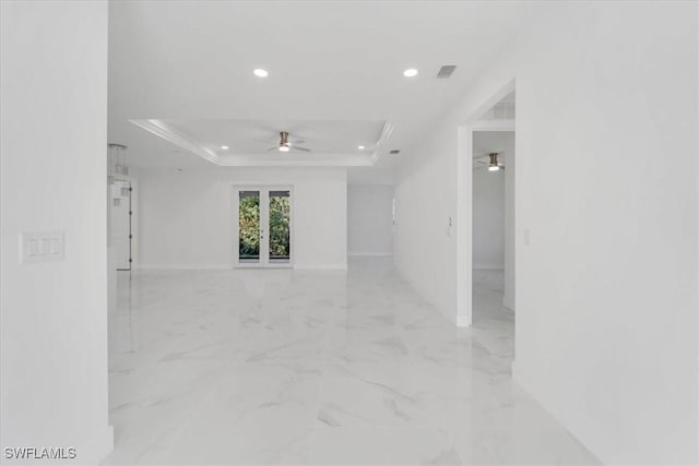 spare room with a tray ceiling, ceiling fan, and ornamental molding