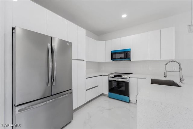 kitchen with decorative backsplash, white cabinetry, sink, and appliances with stainless steel finishes