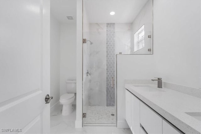 bathroom featuring vanity, a shower with shower door, and toilet