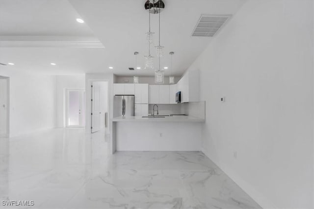 kitchen featuring stainless steel refrigerator, white cabinetry, sink, and hanging light fixtures