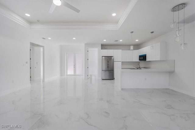 kitchen with stainless steel fridge, ornamental molding, a raised ceiling, white cabinetry, and hanging light fixtures