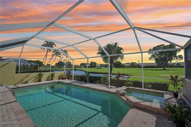 pool at dusk with glass enclosure and a lawn