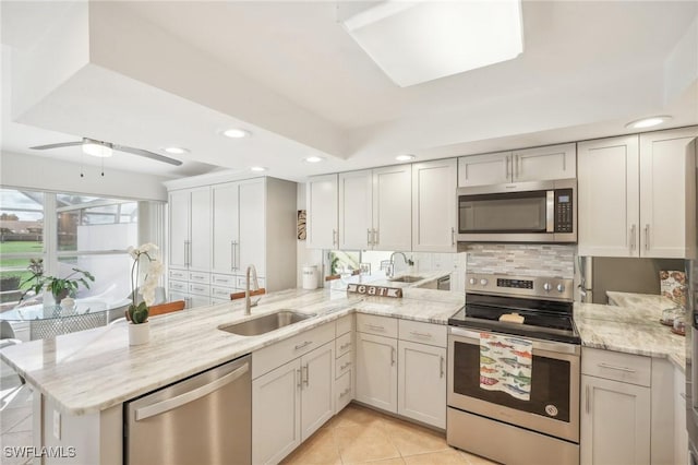 kitchen with kitchen peninsula, light stone counters, sink, and stainless steel appliances