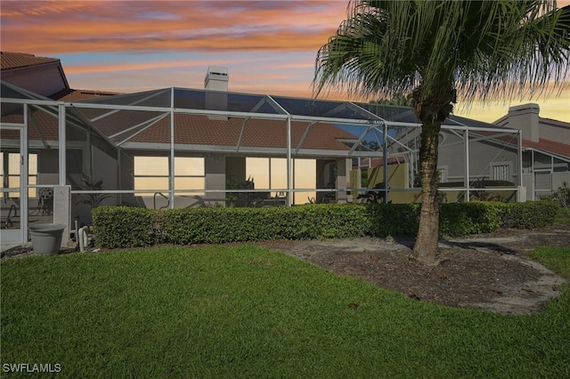 back house at dusk with a yard and a lanai