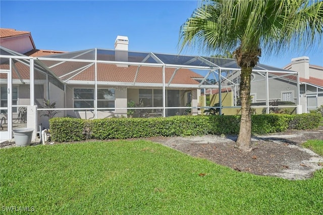 back of property with a yard and glass enclosure