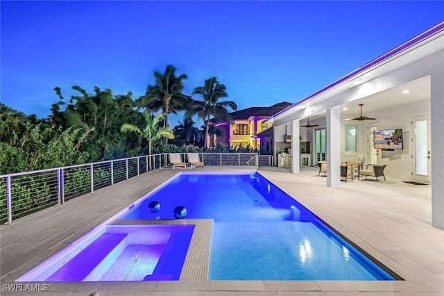 pool at dusk featuring a patio area, ceiling fan, and an in ground hot tub