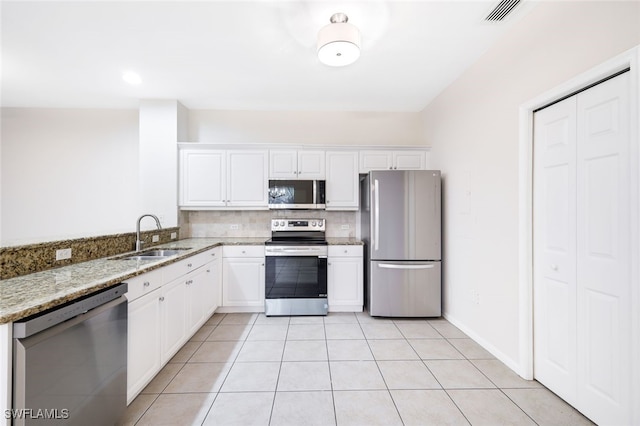 kitchen featuring white cabinetry, sink, stainless steel appliances, light stone counters, and light tile patterned floors