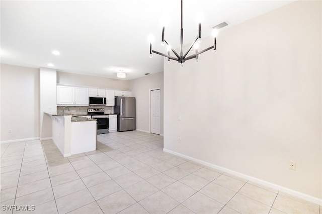 kitchen with white cabinets, light tile patterned floors, appliances with stainless steel finishes, tasteful backsplash, and kitchen peninsula