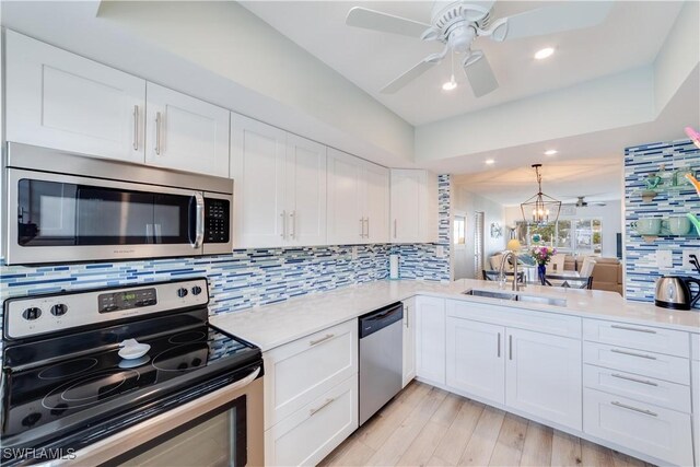 kitchen featuring a chandelier, white cabinets, stainless steel appliances, and light hardwood / wood-style floors