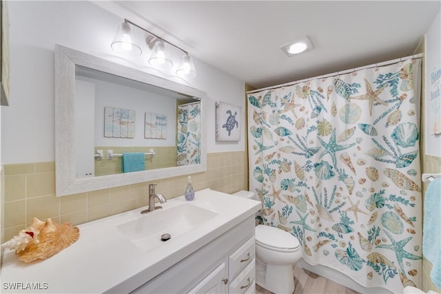 bathroom featuring tile walls, vanity, toilet, and walk in shower