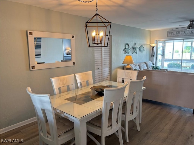 dining space with dark hardwood / wood-style flooring and ceiling fan with notable chandelier