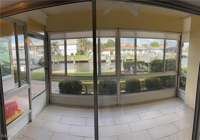 unfurnished sunroom featuring a water view and ceiling fan