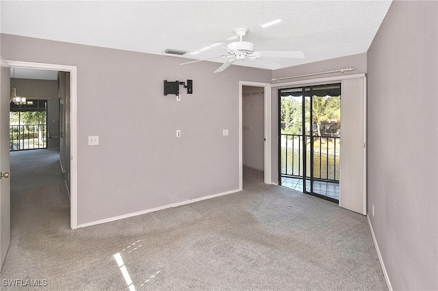 spare room with ceiling fan with notable chandelier, carpet floors, and a textured ceiling