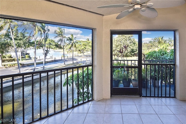 unfurnished sunroom with ceiling fan and a water view