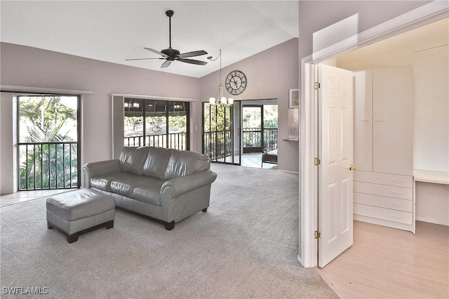 carpeted living room featuring ceiling fan with notable chandelier and high vaulted ceiling