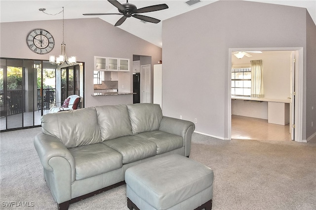 carpeted living room with ceiling fan with notable chandelier and high vaulted ceiling