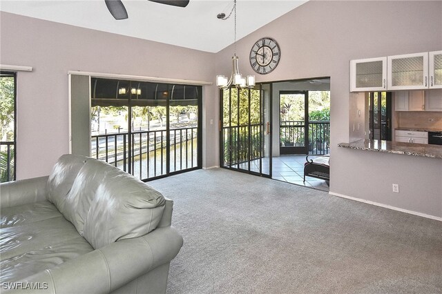 living room featuring light carpet, ceiling fan with notable chandelier, a water view, and high vaulted ceiling